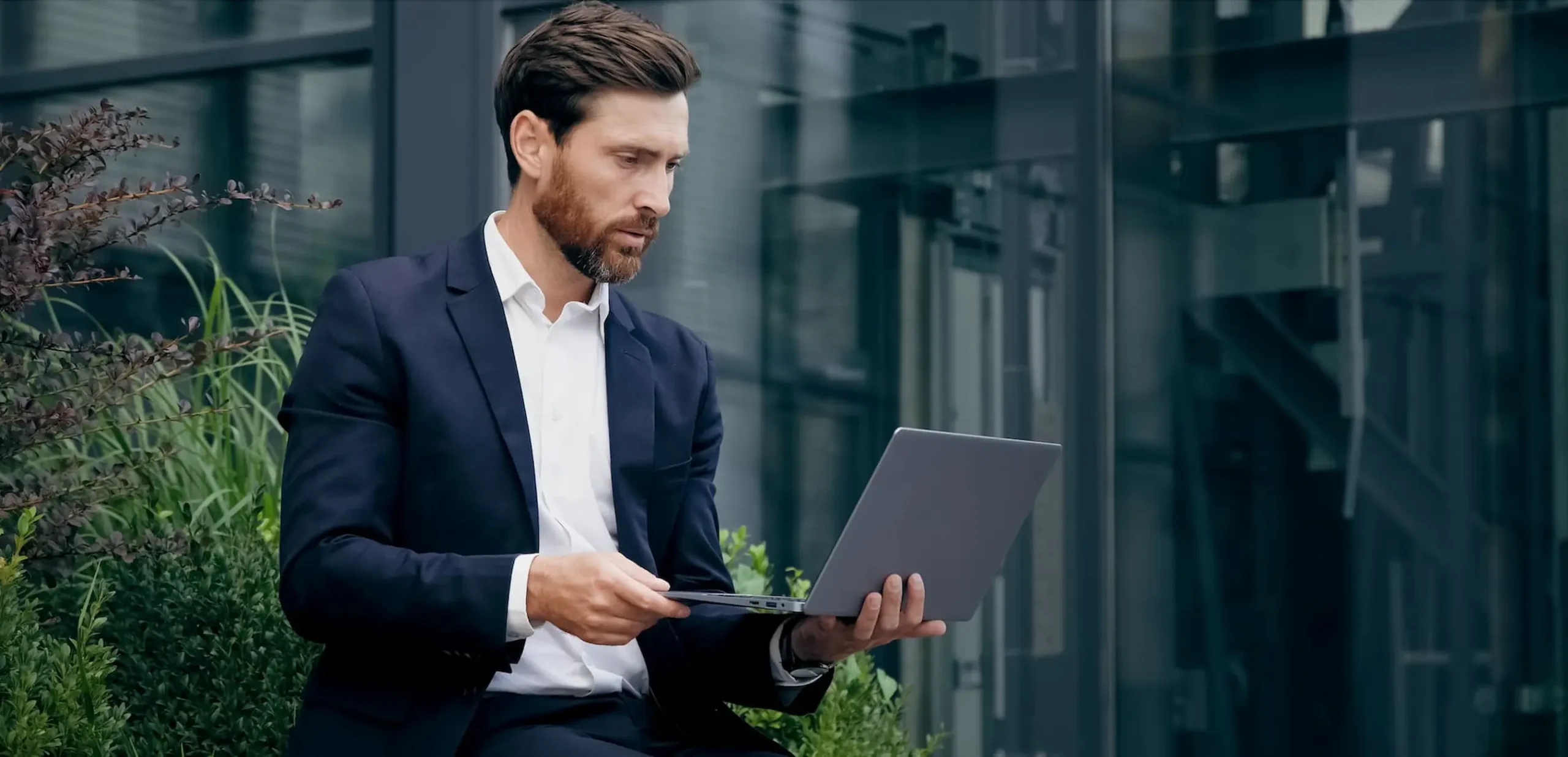 Versicherungsberater sitzt draussen und vereinbart die Termine am Laptop.